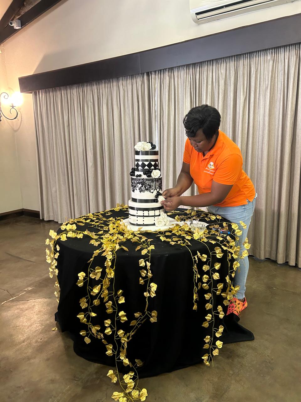 Baker placing sugar roses on a black and white couture wedding cake
